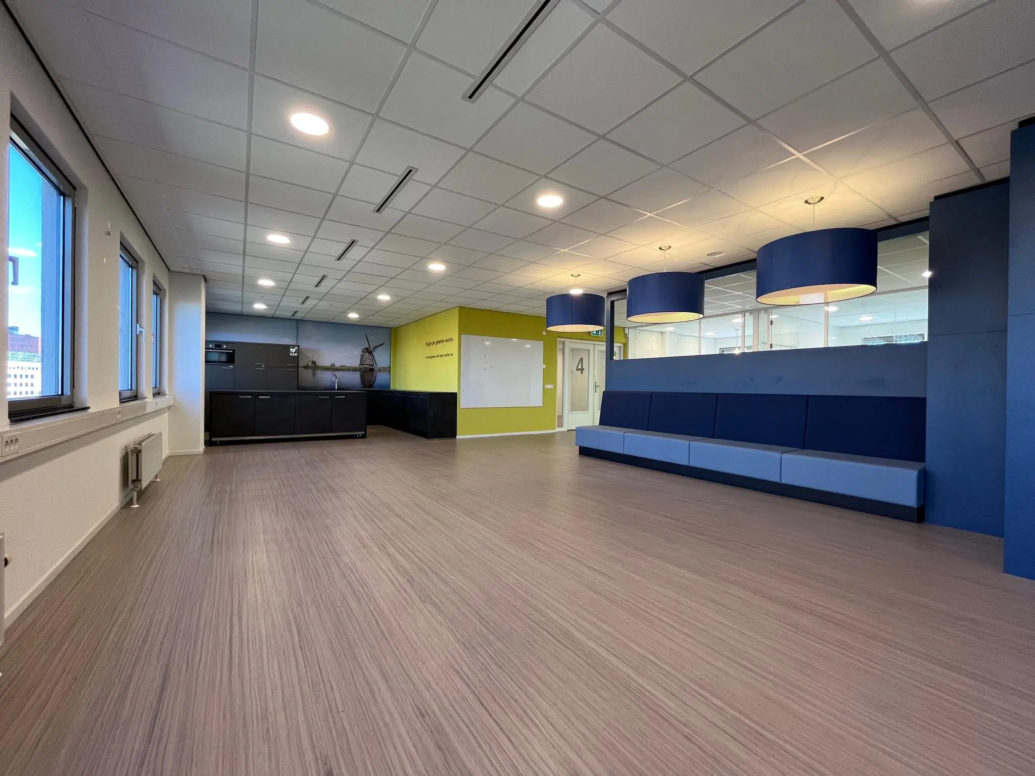 Moderne wachtruimte met zithoek, keukenblok en grote ronde plafondlampen aan de Barchman Wuytierslaan.